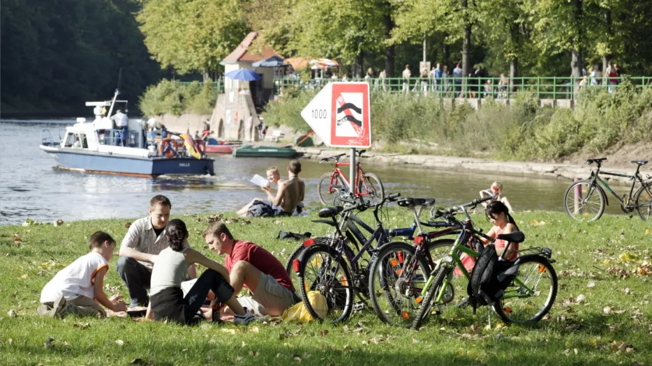 Junge Menschen sitzen zusammen an der Saale auf einer Wiese und unterhalten sich, daneben stehen ihre Fahrräder.