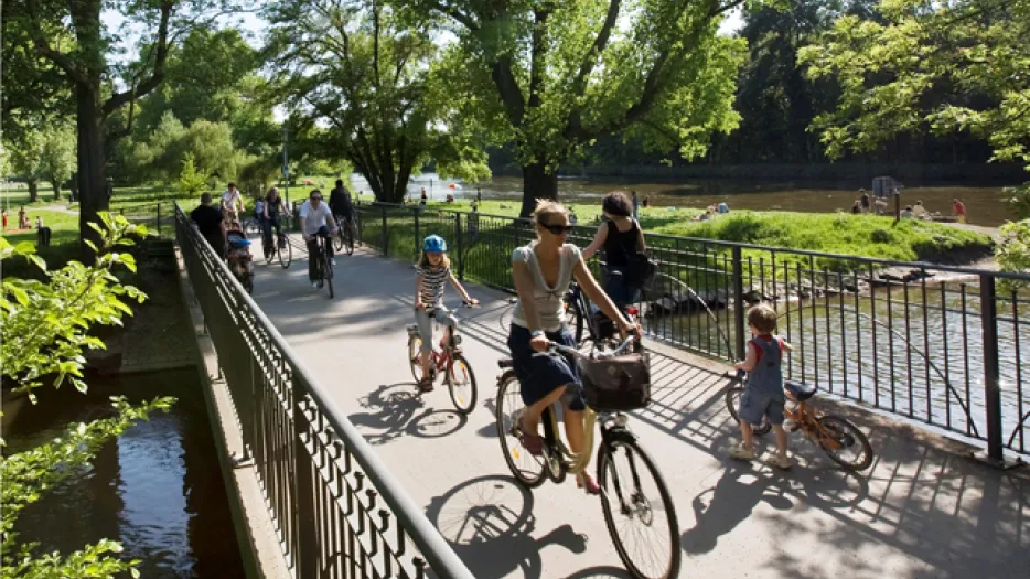 Fahrradfahrer auf einer Brücke über der Saale, im Hintergrund ist eine grüne Wiese zu sehen..